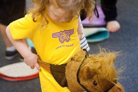 Image shows toddler enjoying Music Bugs class with hobby horse