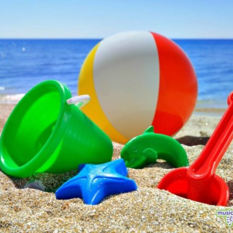 Image shows beach scene with bucket, spade and beach ball